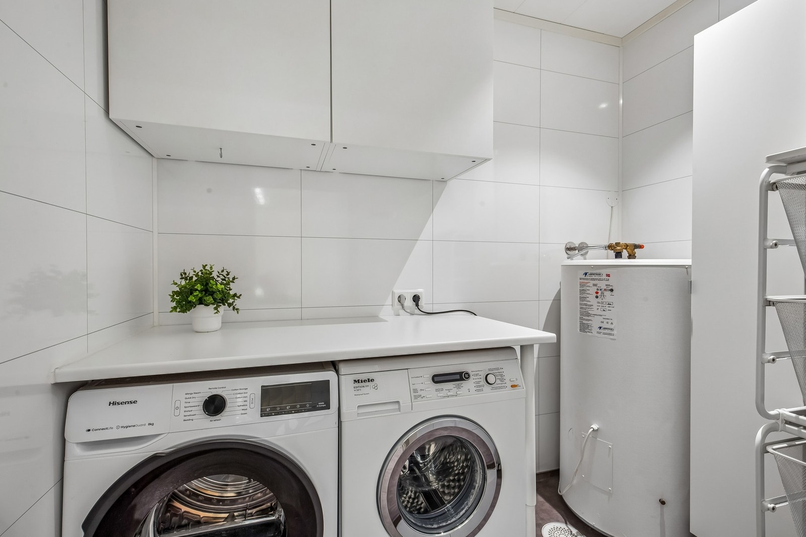 Praktisk vaskerom i bakkant av badet med opplegg for og plass til både vaskemaskin og tørketrommel. Galleribilde