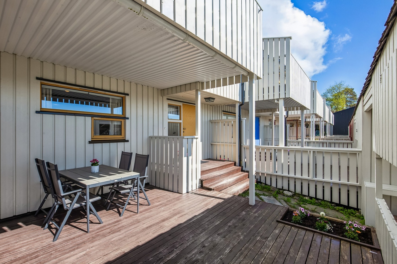 Boligen har flere fine uteplasser for avslapping og lek, bl.a. denne delvis overbygde terrassen på ca. 20 m² ved inngangspartiet. Galleribilde