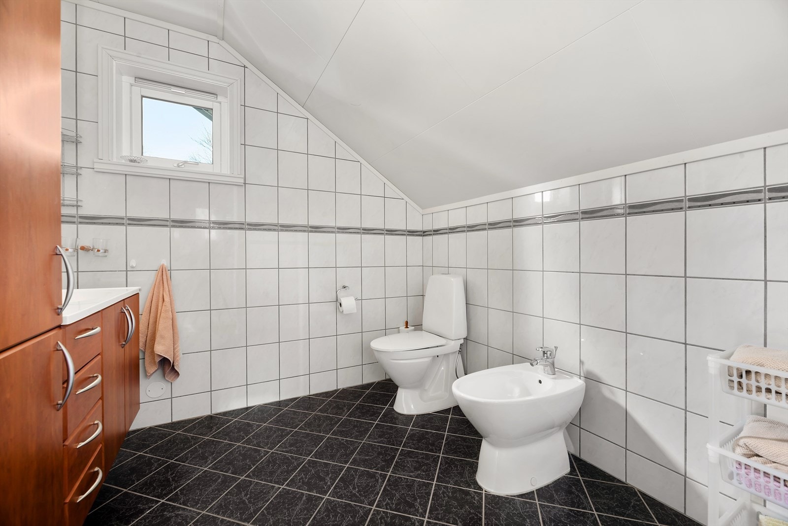 Badet i loftetasjen har fliser på vegger og gulv, elektriske varmekabler og bidé, Fotograf: Maren Terese Forsbakk Galleribilde