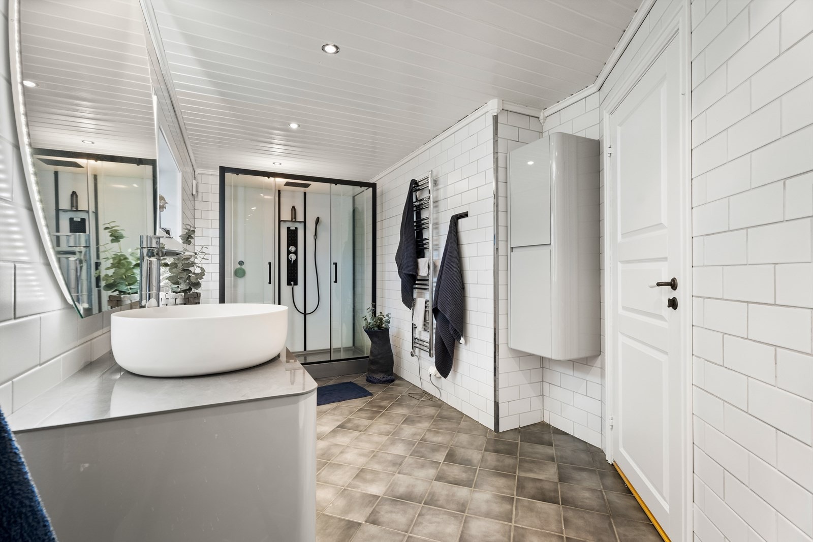 Romslig servantinnredning med god oppbevaringsplass og et stort, bakbelyst speil. Galleribilde