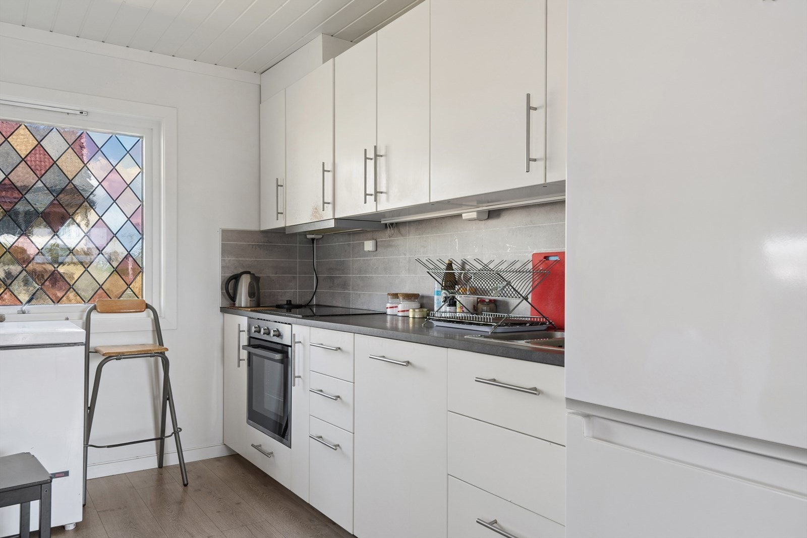 Kjøkkenet i første etasje har innredning med glatte fronter, dobbel kjøkkenkum og plass til frittstående kjøle-/fryseskap. Galleribilde