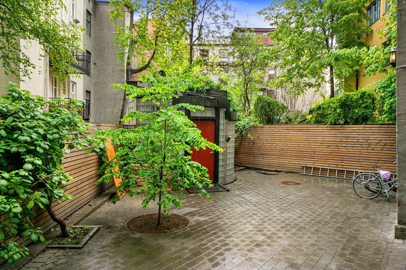 Sameiet disponerer en bakgård med belegningsstein, beplantning og sykkelparkering. Galleribilde