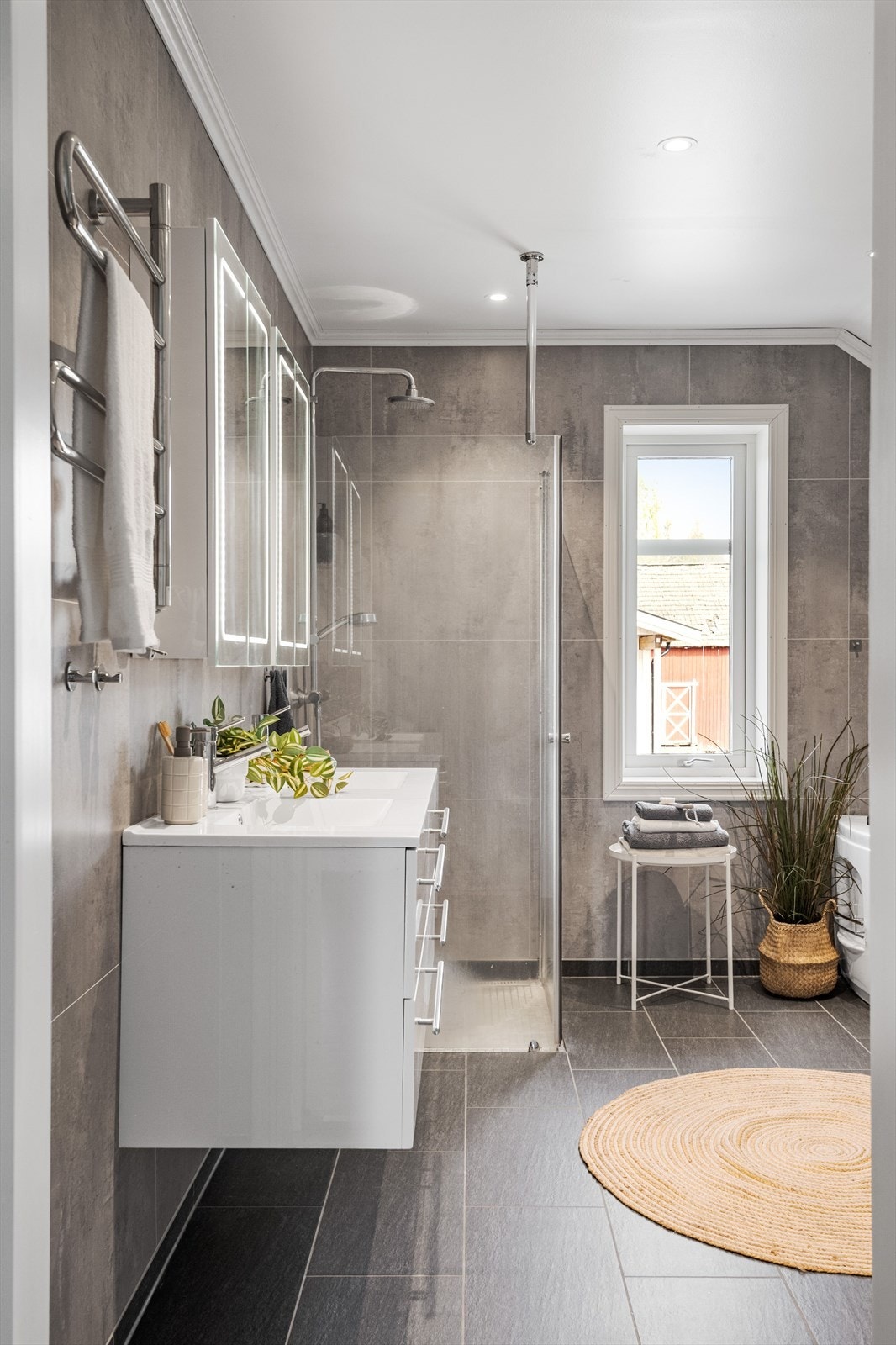 Stort og moderne baderom i 2. etasje fra byggeåret 2018. Baderommet har mørke fliser på gulv, vannbåren gulvvarme, våtromsplater på veggene, downlights i himlingen og avtrekk via balansert ventilasjon. Galleribilde