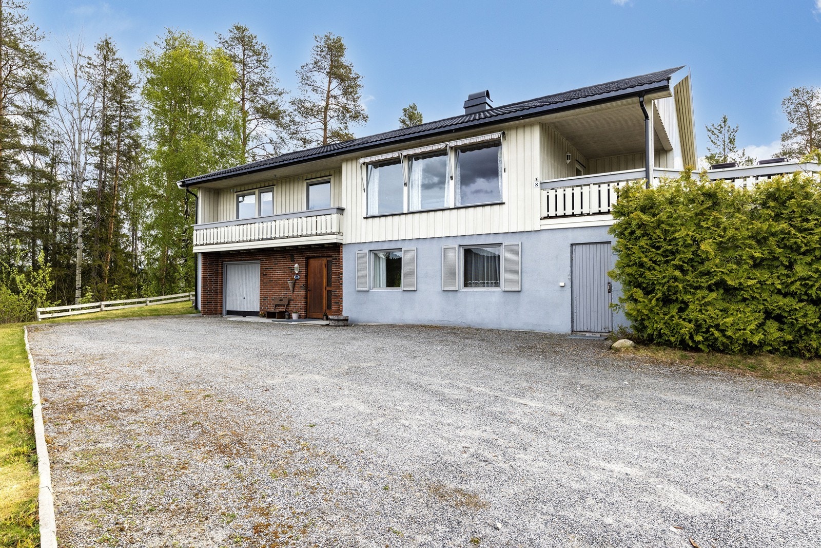 Integrert garasje med vippeport, samt hovedinngang i underetasjen. Grunnmuren er dels forblendet med teglstein. Galleribilde