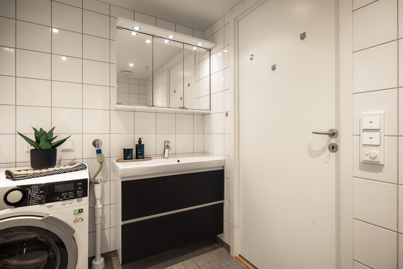 Badet er innredet med servant nedfelt i skap, speilskap med belysning og opplegg for vaskemaskin. Galleribilde