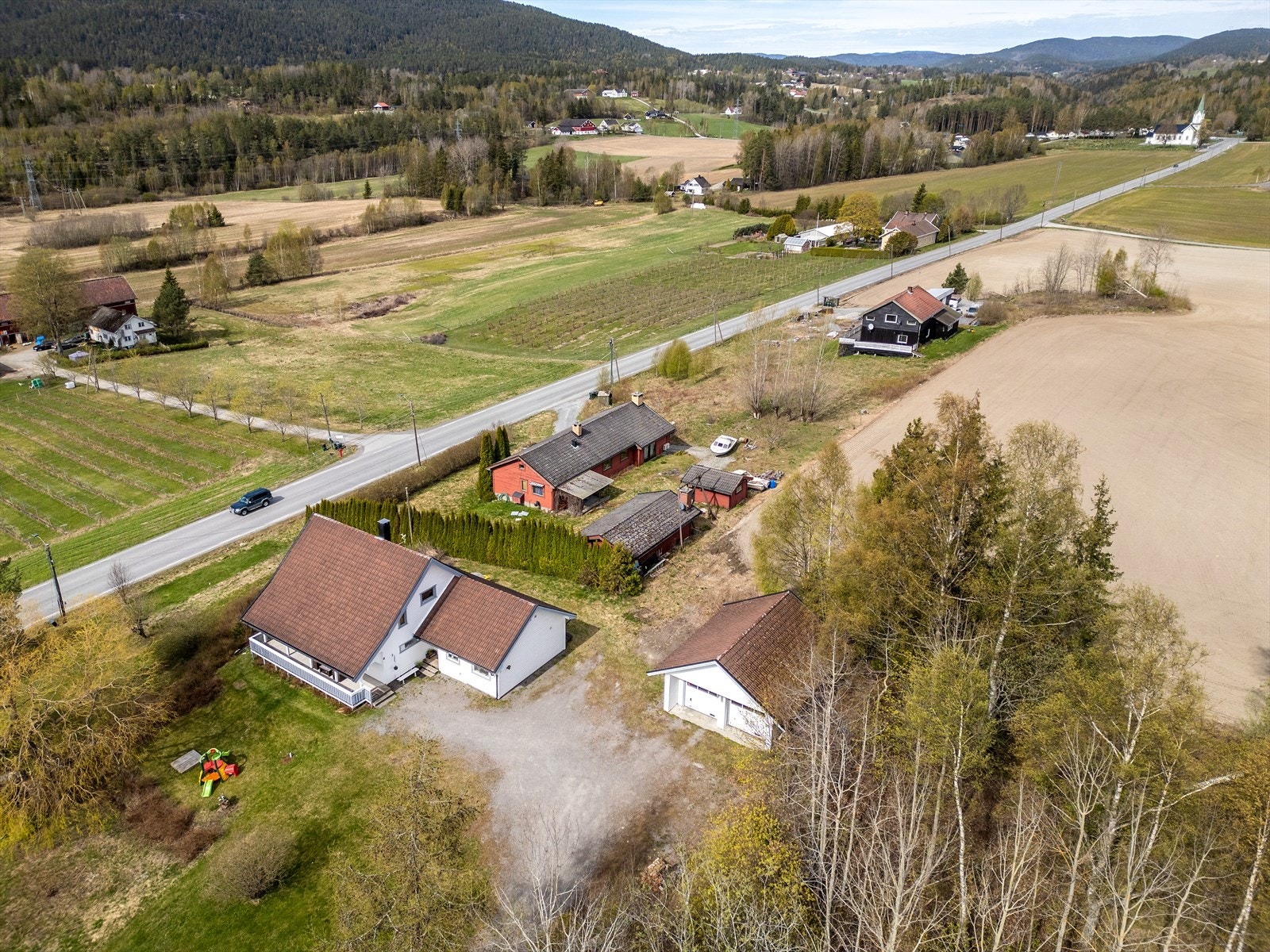 Gruset innkjørsel og gårdsplass med rikelig med parkeringsmuligheter. Galleribilde