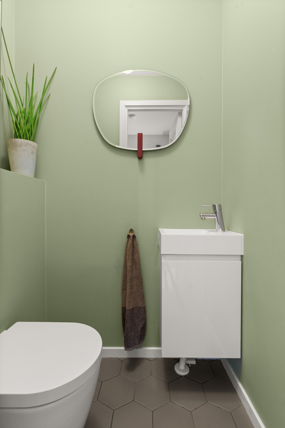 Separat WC i 1. etasje med vegghengt toalett, liten servant med underskap og hexagonfliser på gulvet med varmekabler. Malte vegger. Galleribilde
