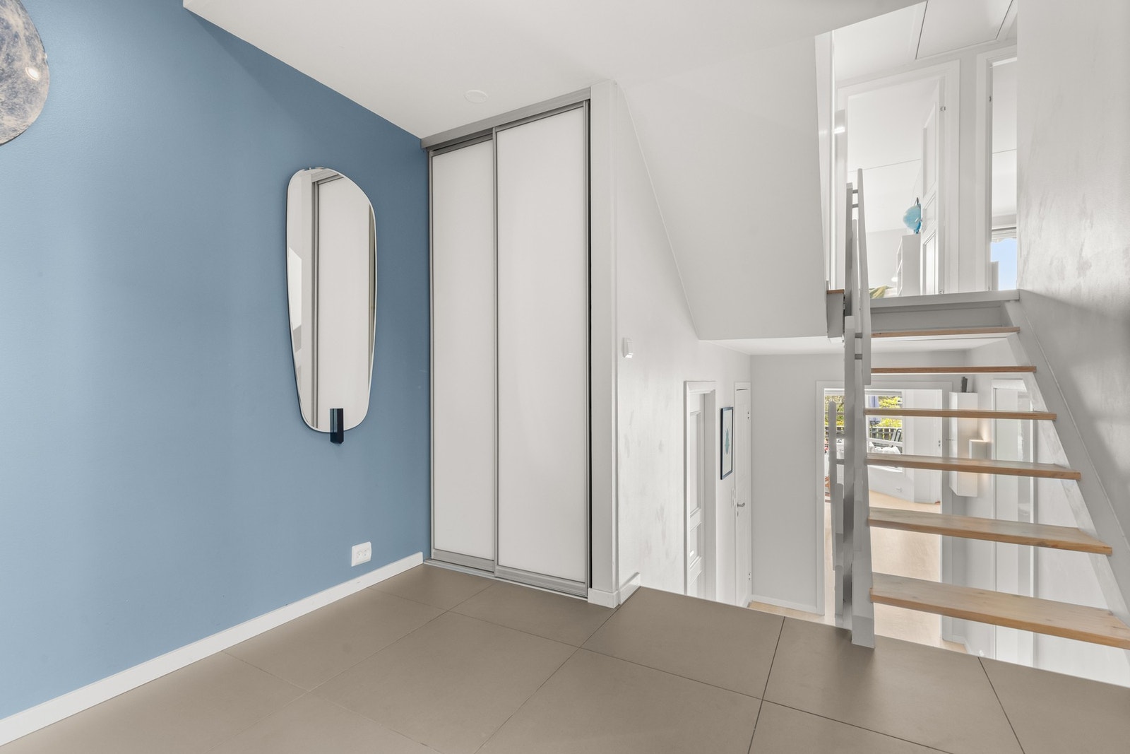 En fastmontert garderobe med skyvedører gir god oppbevaringsplass fra første steg inn. Trappen herfra leder deg opp til boligens hovedplan. Galleribilde