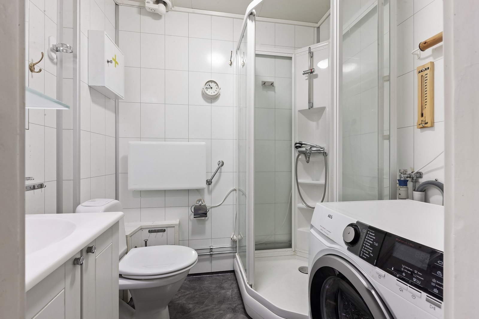 Badet har lys innredning med nedfelt servant og skap under, dusjkabinett, toalett og opplegg for vaskemaskin. Galleribilde