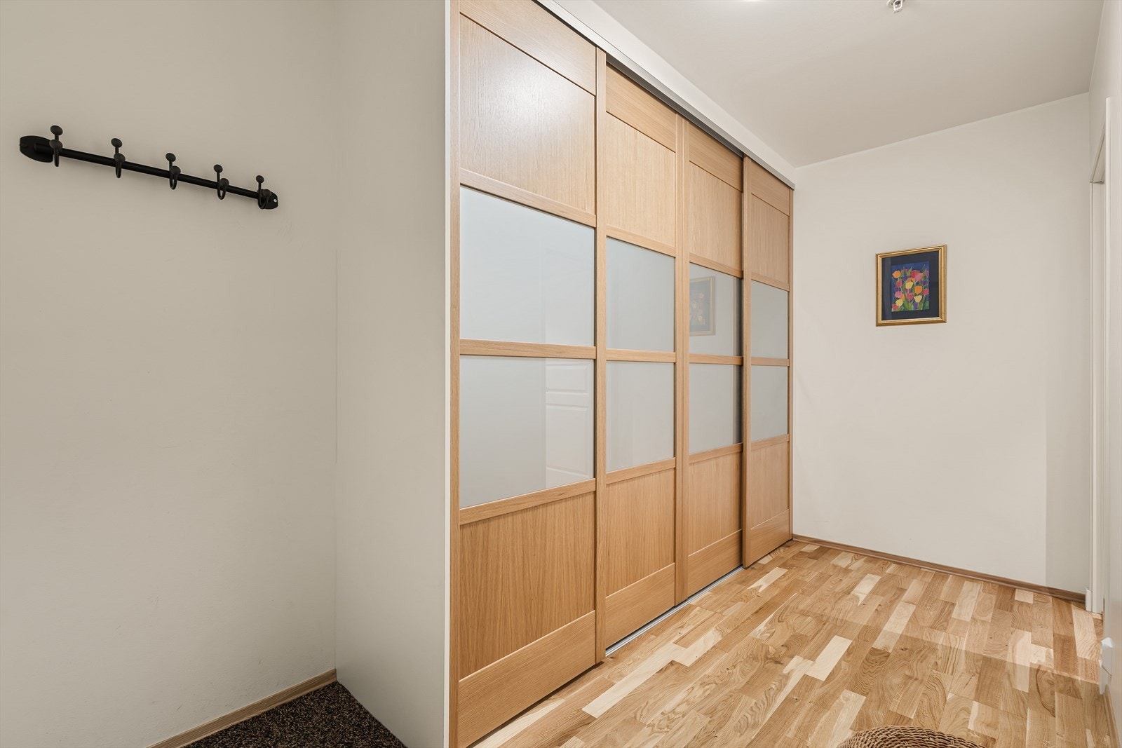 Entré og gang har parkett på gulv og lysmalte vegger i likhet med resten av boligen. En romslig skyvedørsgarderobe med speil gir rikelig med oppbevaringsplass Galleribilde