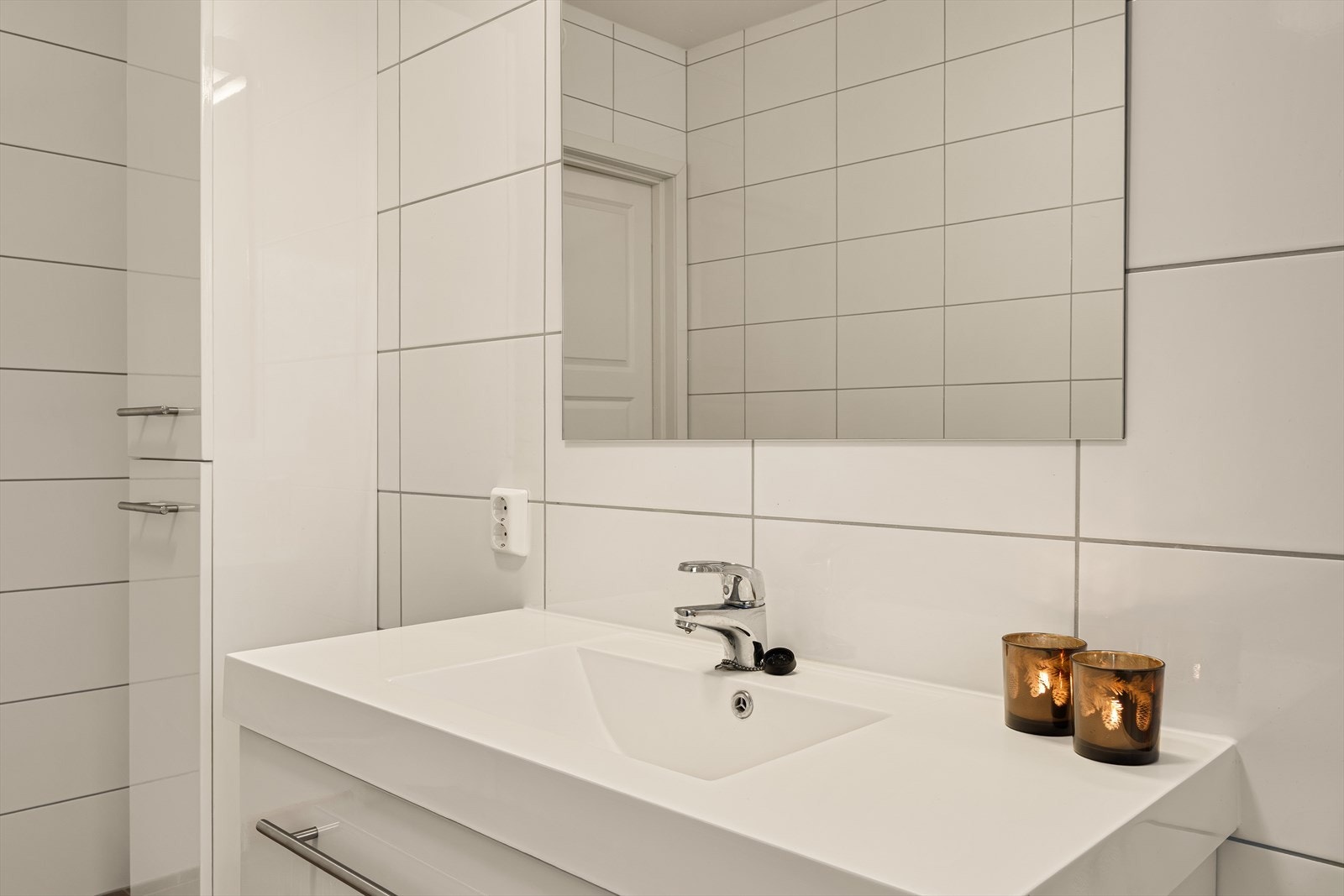 Badet inneholder heldekkende servant med møblement, matchende veggskap, vegghengt toalett, dusjgarnityr og innfellbart dusjhjørne. Galleribilde