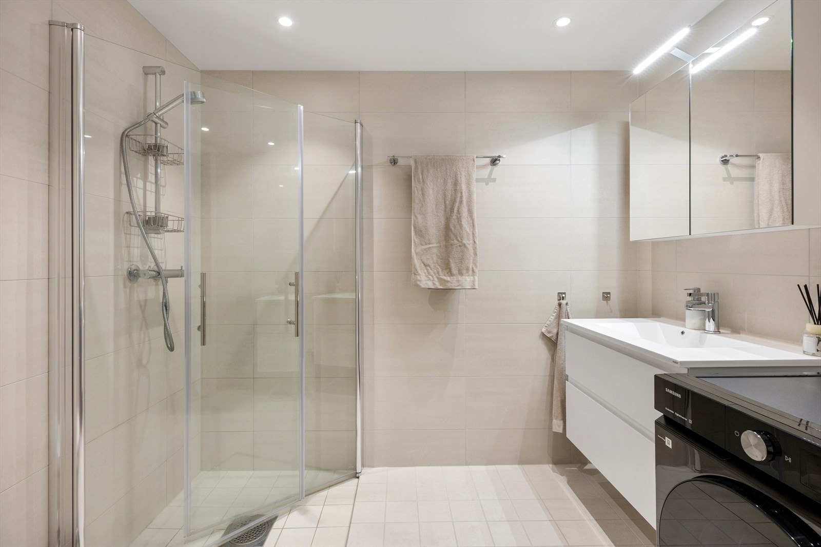 Badet har dusj med innfellbare dører i herdet glass, vegghengt toalett og servantinnredning. Galleribilde