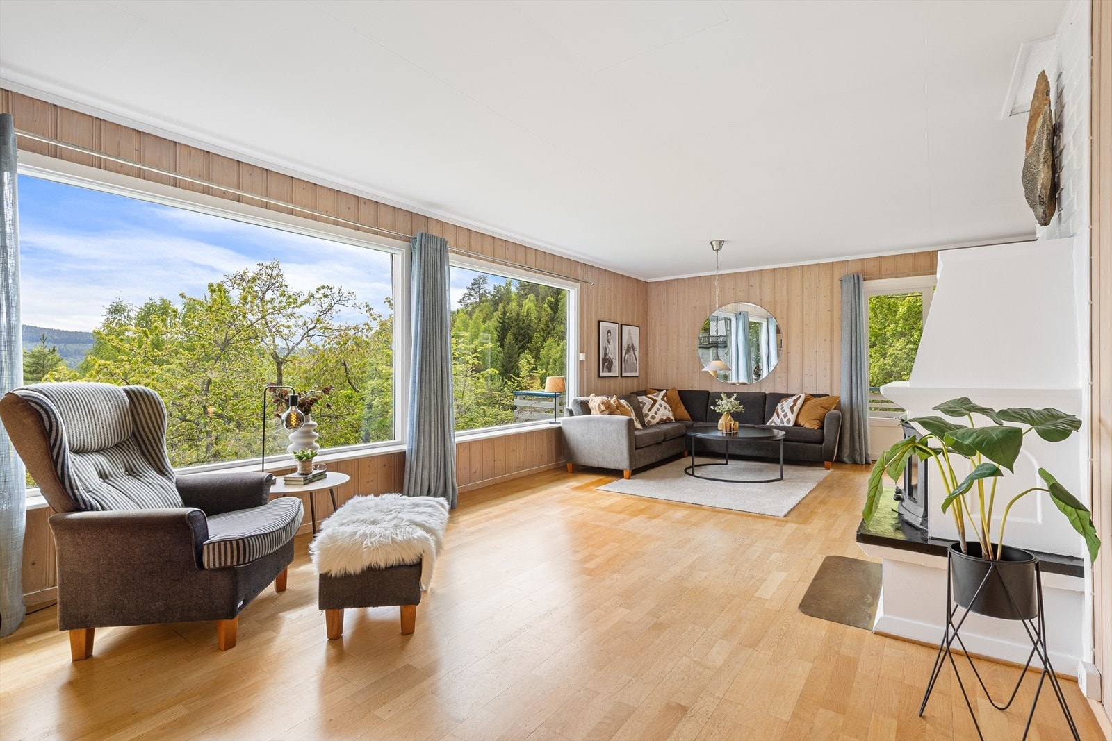 Store vindusflater i stuen gir rikelig med naturlig lys og rammer inn utsikten mot skogen. Galleribilde