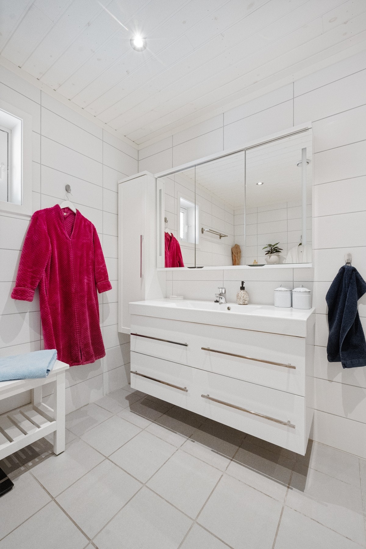 Badet fremstår delikat med flislagte overflater, gulvvarme, vegghengt toalett og dusjhjørne med glassdører. Galleribilde