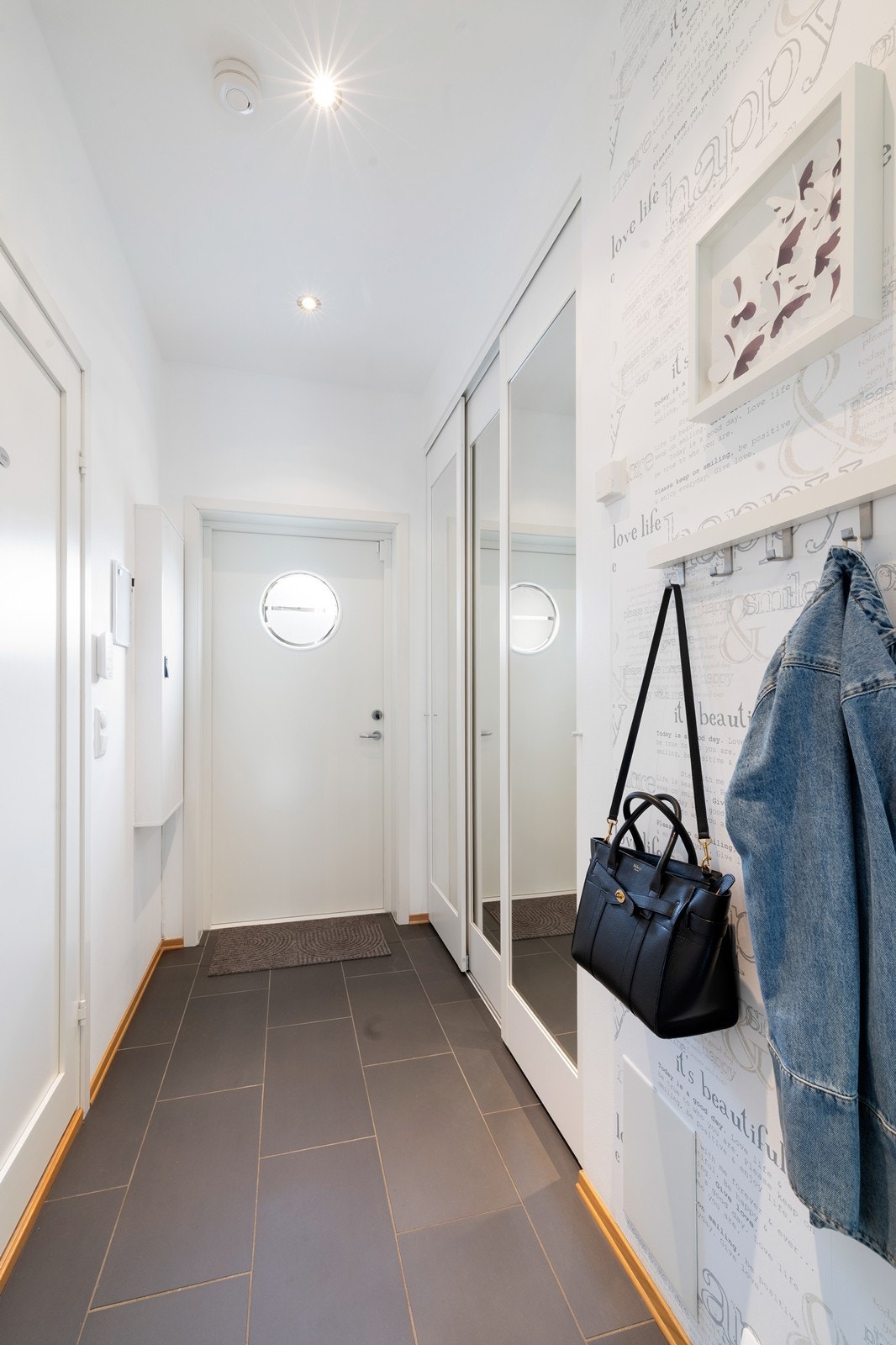 Det er god plass til å henge av seg klær i inngangsparti. Legg også merke til romslig skyvedørsgarederrobe med speil og fliser på gulv. Galleribilde