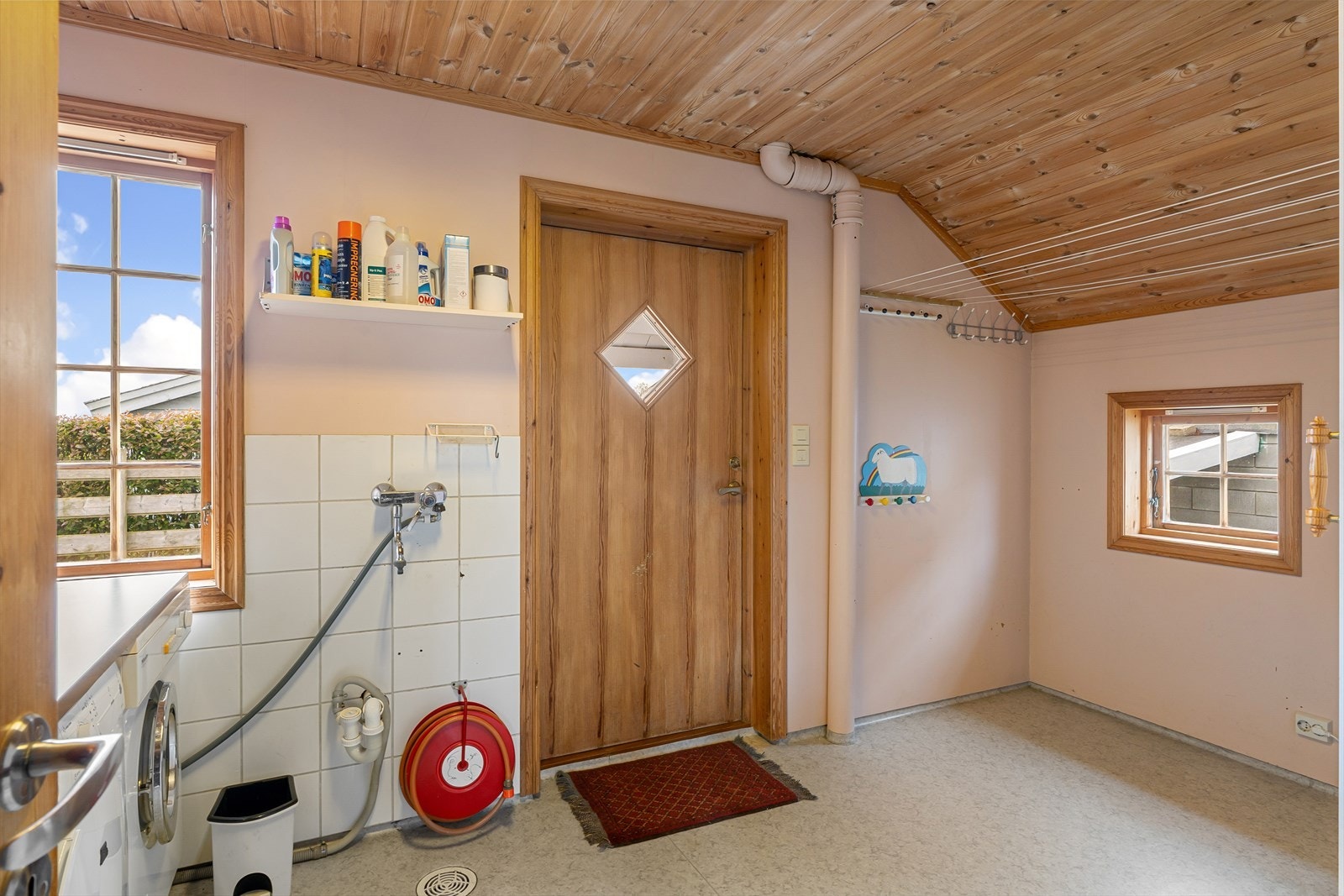 Praktisk vaskerom med vinylbelegg på gulv, opplegg for vaskemaskin og egen bi-inngang. Galleribilde