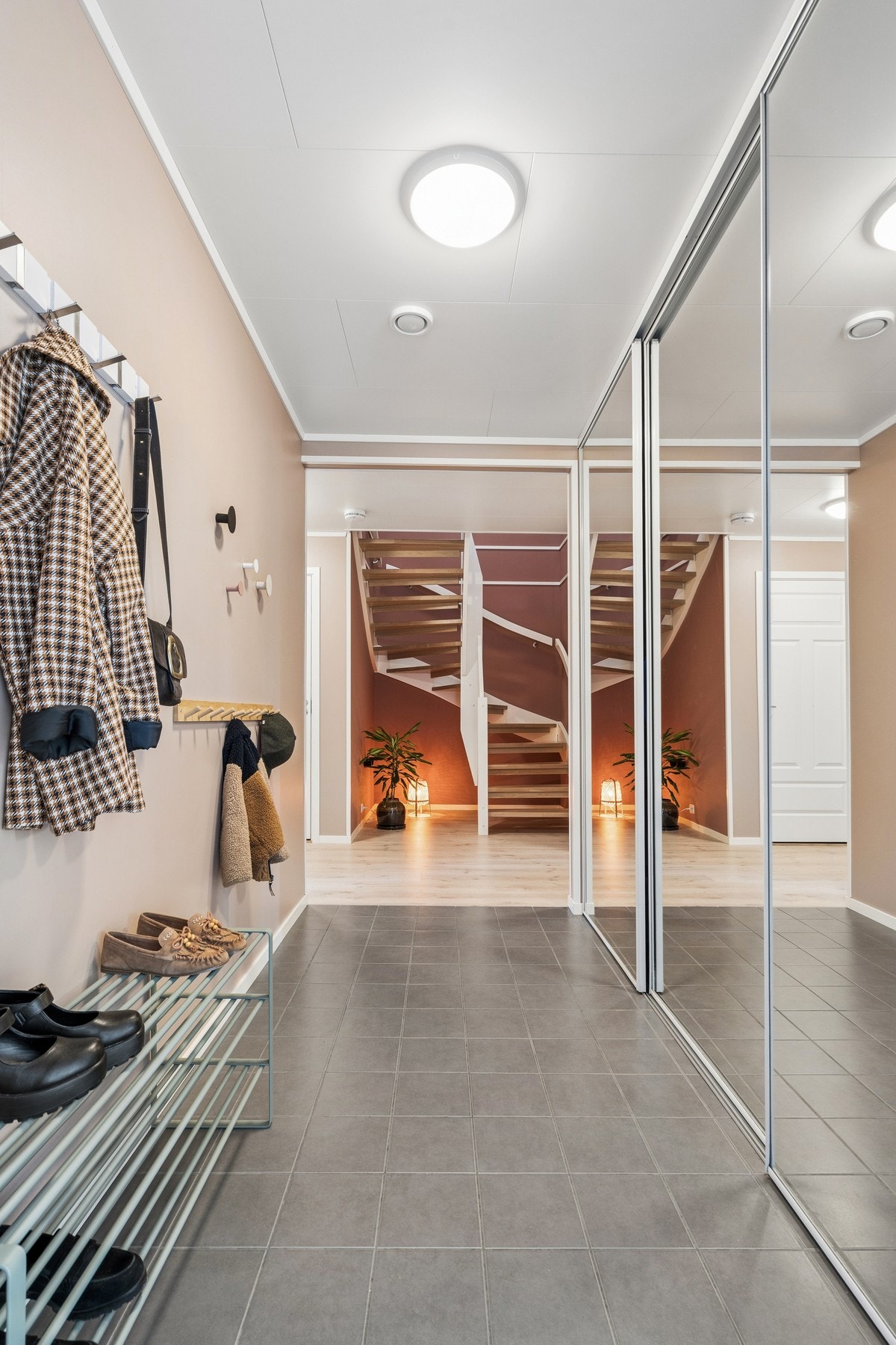Romslig entré med flislagt gulv m/varmekabler og en stor skyvedørsgarderobe med speilfronter for rikelig med oppbevaring. Galleribilde