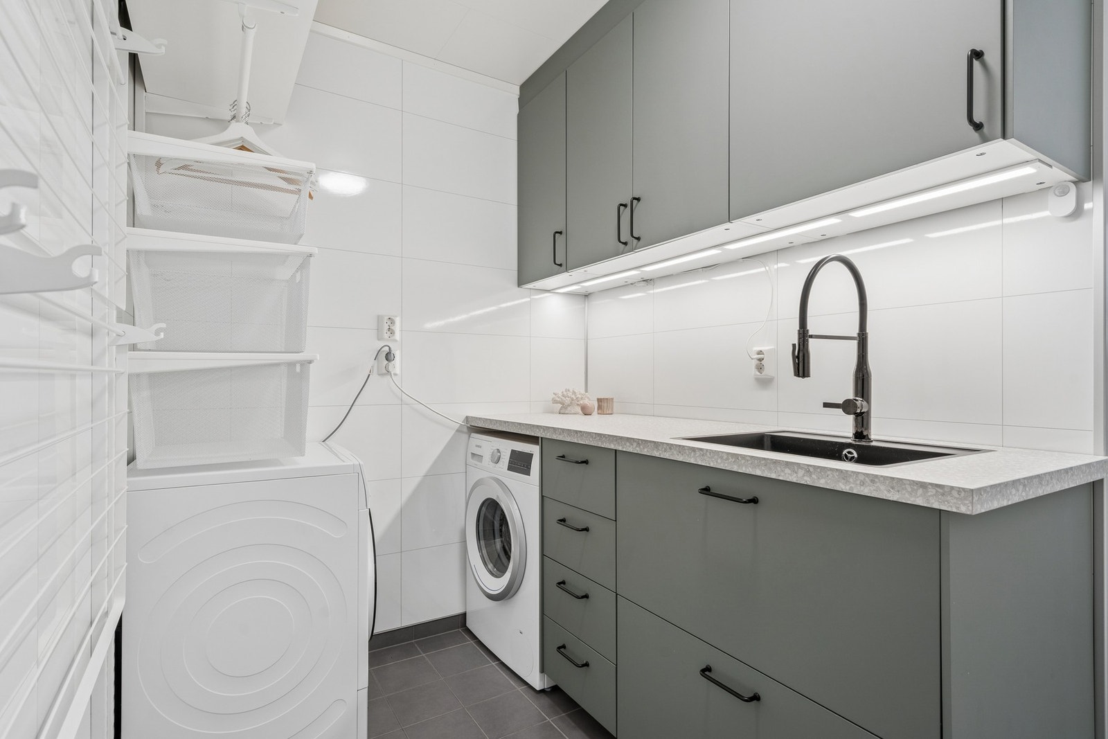Praktisk og velutstyrt vaskeromsdel i tilknytning til badet. Innredningen har gode oppbevaringsmuligheter og opplegg for vaskemaskin og tørketrommel. Galleribilde
