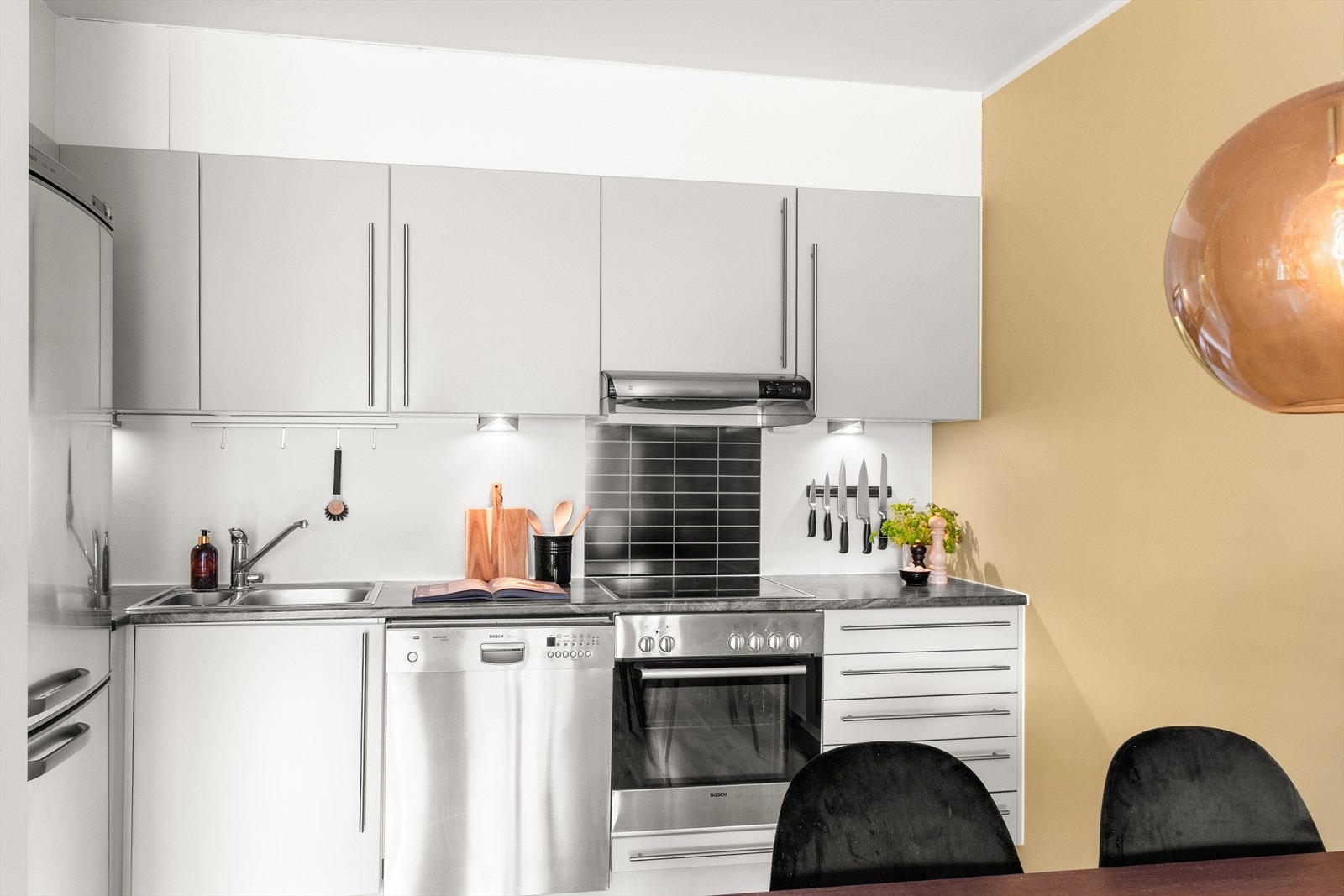 Slette fronter med laminat benkeplate med kum i rustfritt stål. Ventilator, stekeovn og platetopp og er integrert i innredningen, samt frittstående kjøleskap og oppvaskmaskin. Galleribilde