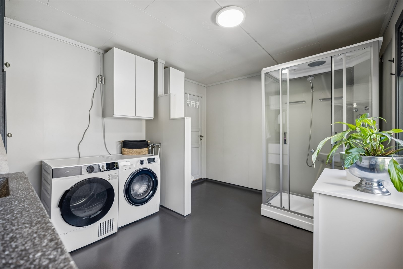 Kombinert bad/vaskerom med praktisk dusjkabinett og opplegg for både vaskemaskin og tørketrommel. Galleribilde