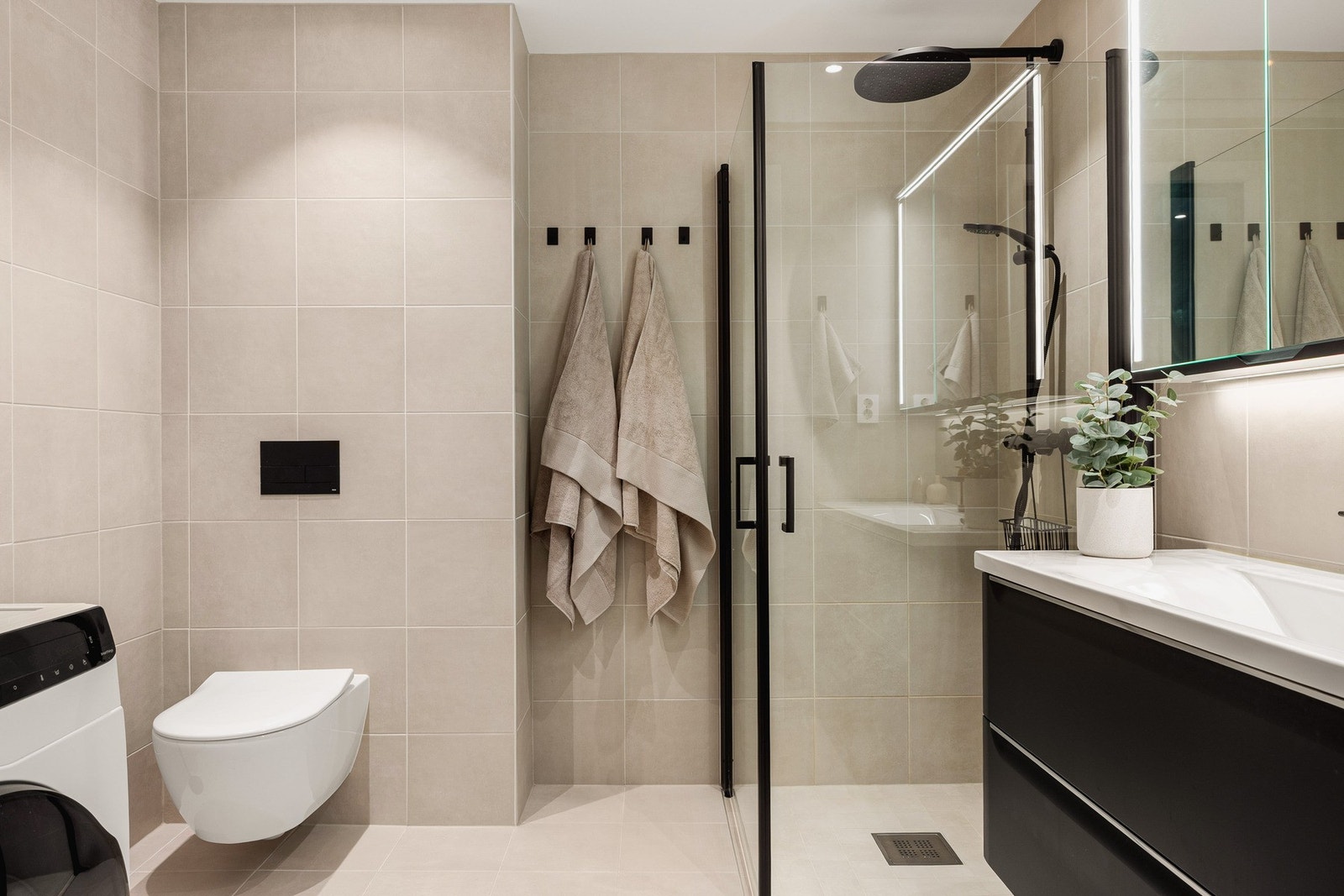 Badet måler 5,7 kvm og er oppgradert med tilvalg av fliser, oppgradering av toalett og større baderomsmøbel. Galleribilde