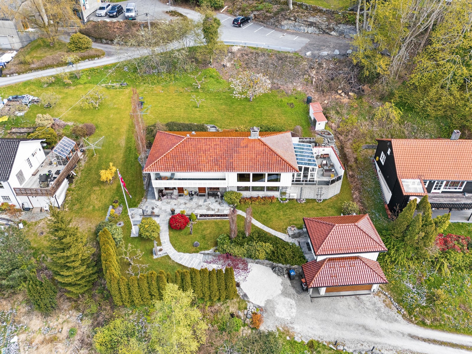 Oversiktsbilde viser eiendommens ovenfra og dens velholdte utendørsområde. Sunnhordland museum ligger like bak eiendommen. Galleribilde