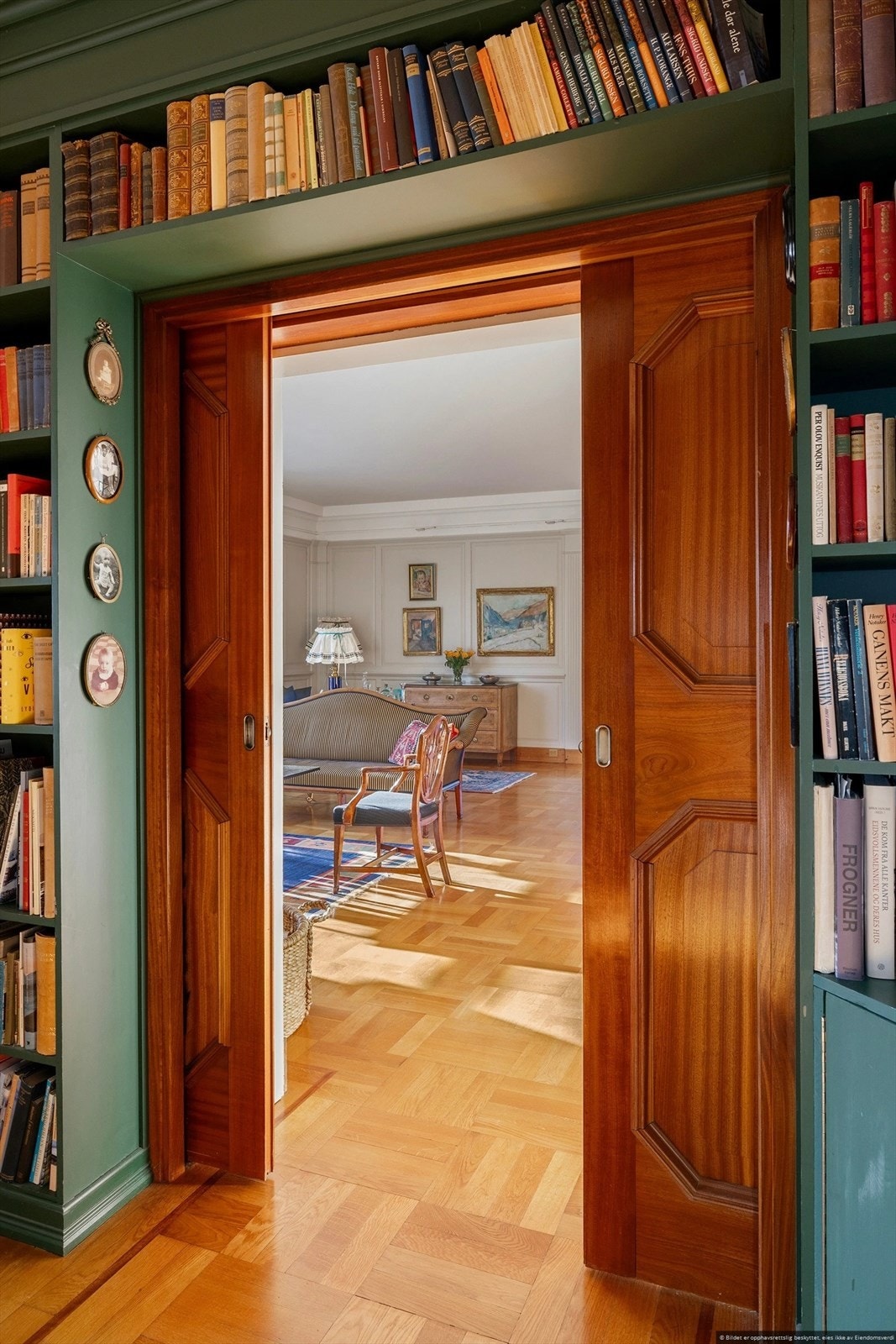 Doble skyvedører i edeltre forbinder biblioteket med hovedstuen. Galleribilde