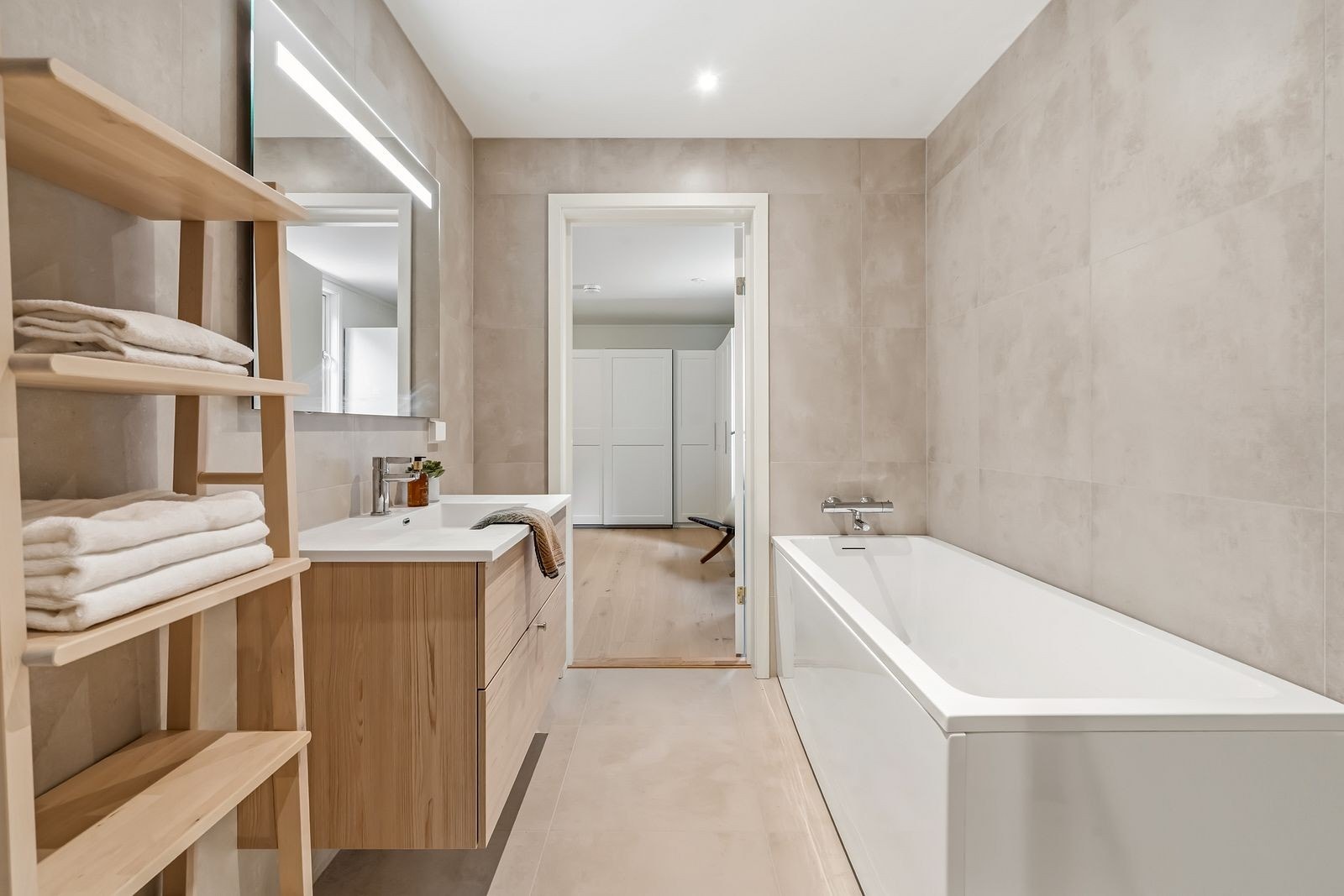 Badet er stilrent innredet med dusjhjørne med innfellbare glassdører, badekar, servantinnredning og vegghengt toalett. Galleribilde