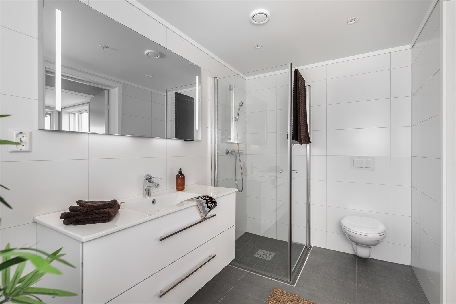 Badet har vegghengt toalett og en romslig dusjnisje med innfellbare glassdører. Galleribilde