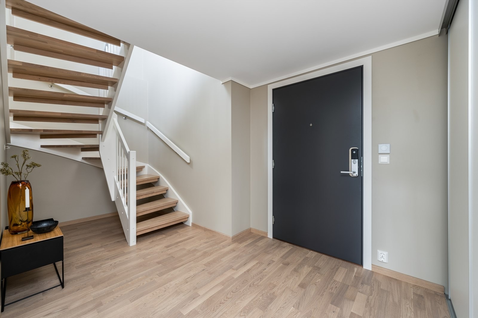En romslig entré ønsker velkommen inn. Trappen i eik fører opp til leilighetens andre etasje. Galleribilde