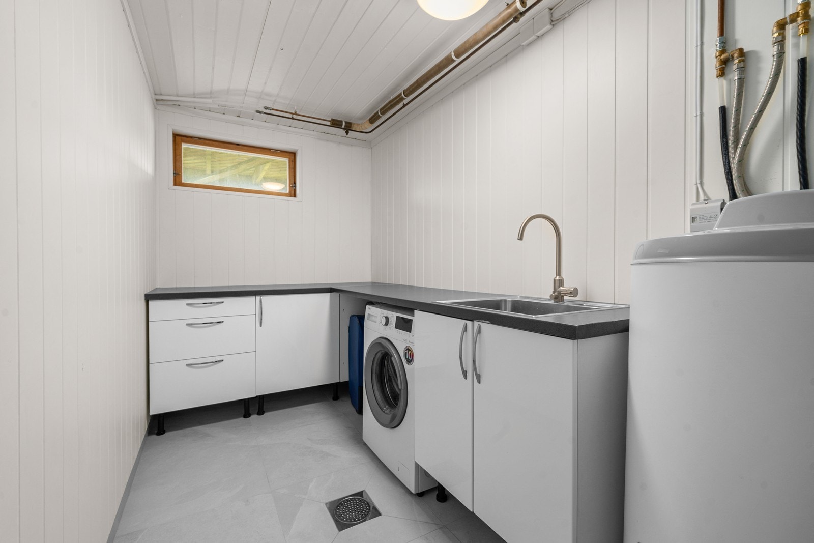 Vaskerommet i kjeller har flis på badet. Utslagsvask, opplegg for vaskemaskin og tørketrommel. Galleribilde