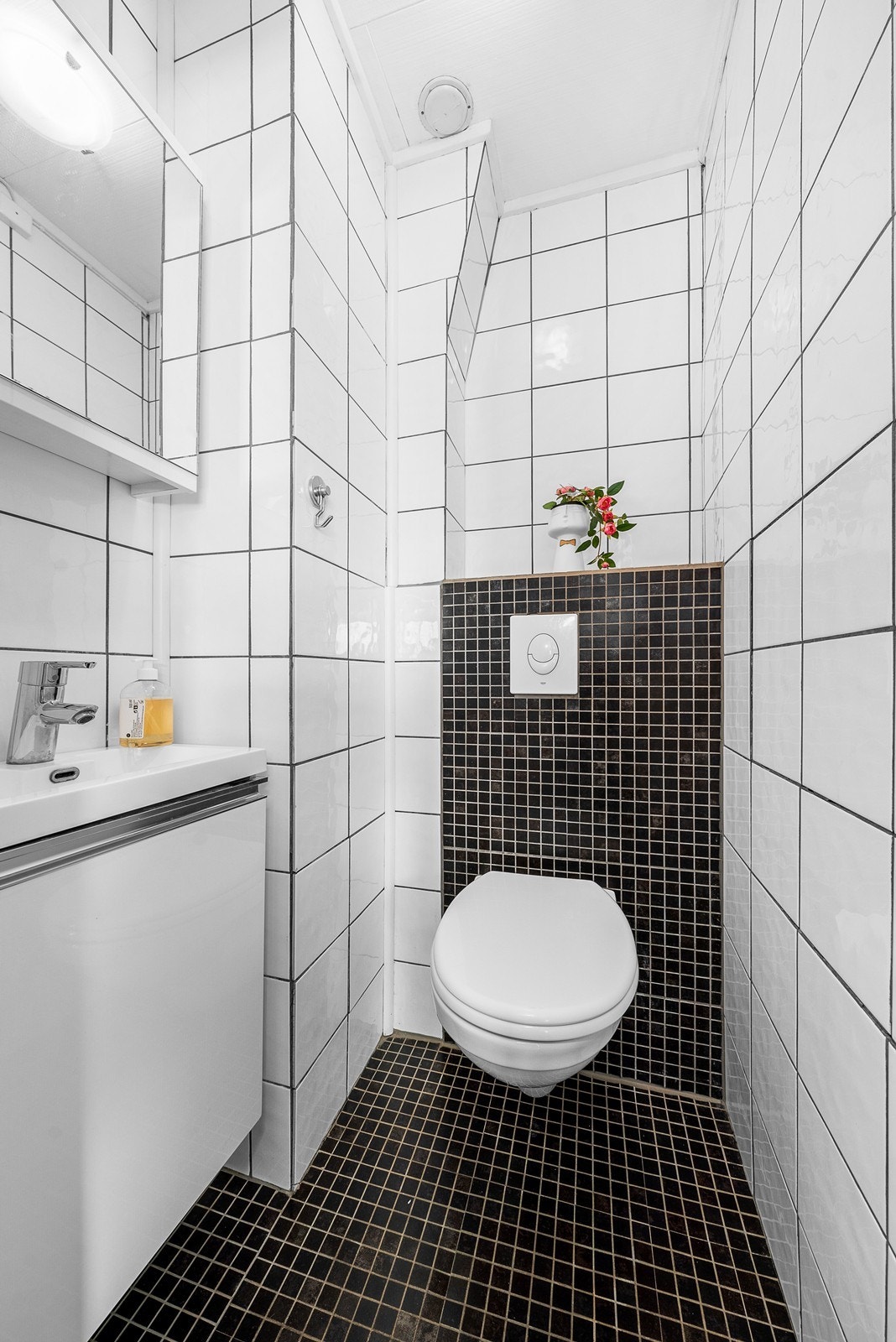 Toalettrom med fliser på vegger og gulv. Rommet er utstyrt med vegghengt wc og servant på vegg. Det er naturlig avtrekk. Galleribilde