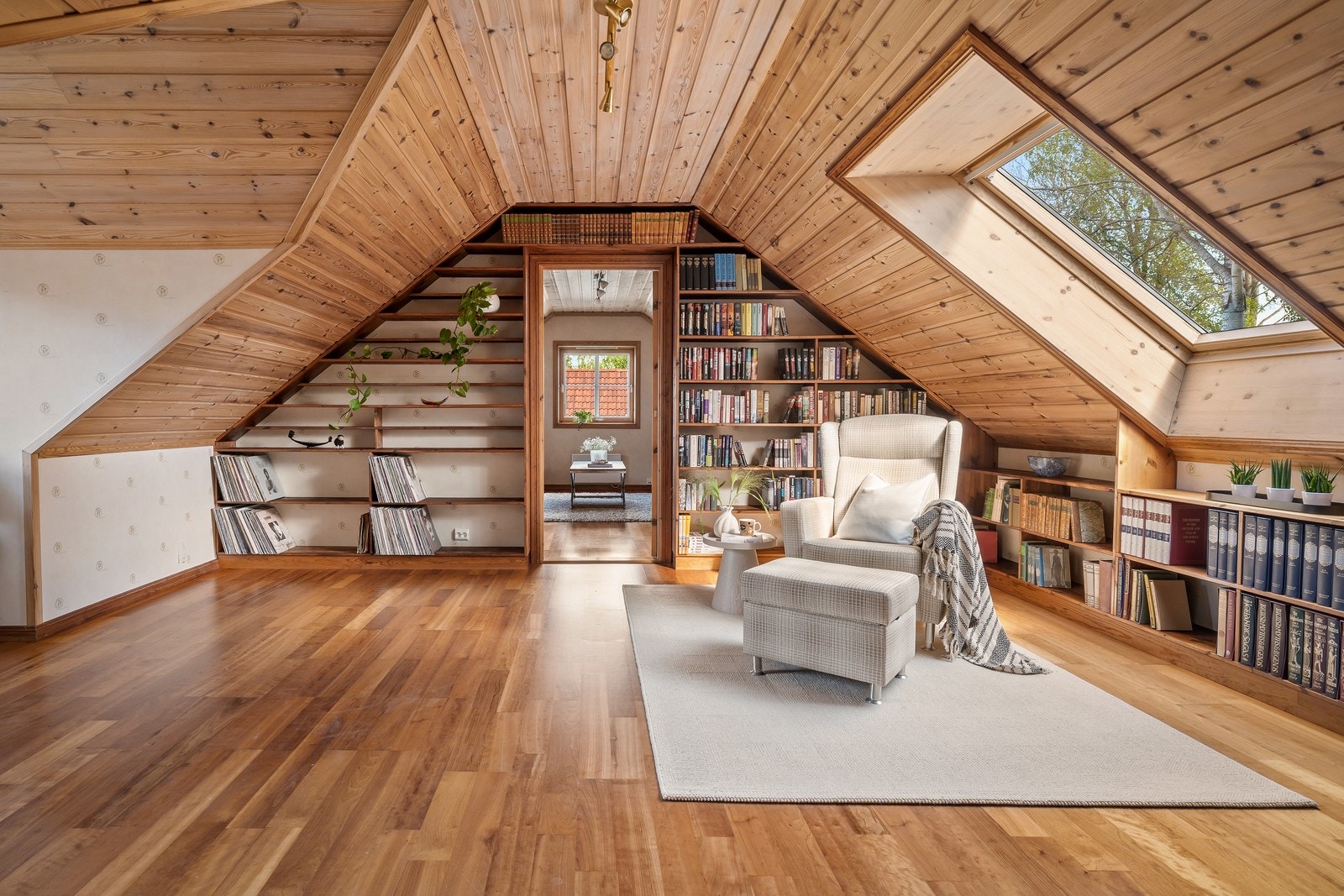 Loftstue med parkettgulv og plassbygde bokhyller i tre. Galleribilde