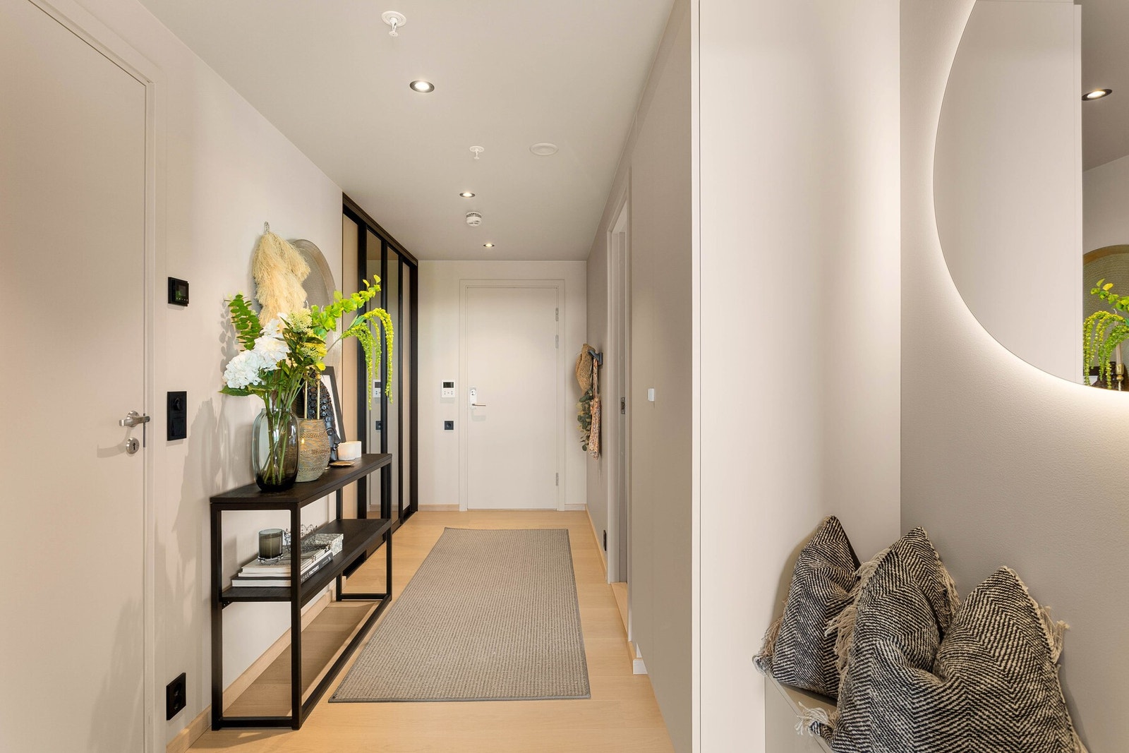 Hele leiligheten har glatte, lysmalte vegger i en delikat lys beige tone, listefrie himlinger med integrerte downlights samt elegant enstavs parkett som understreker den moderne og eksklusive følelsen. Galleribilde