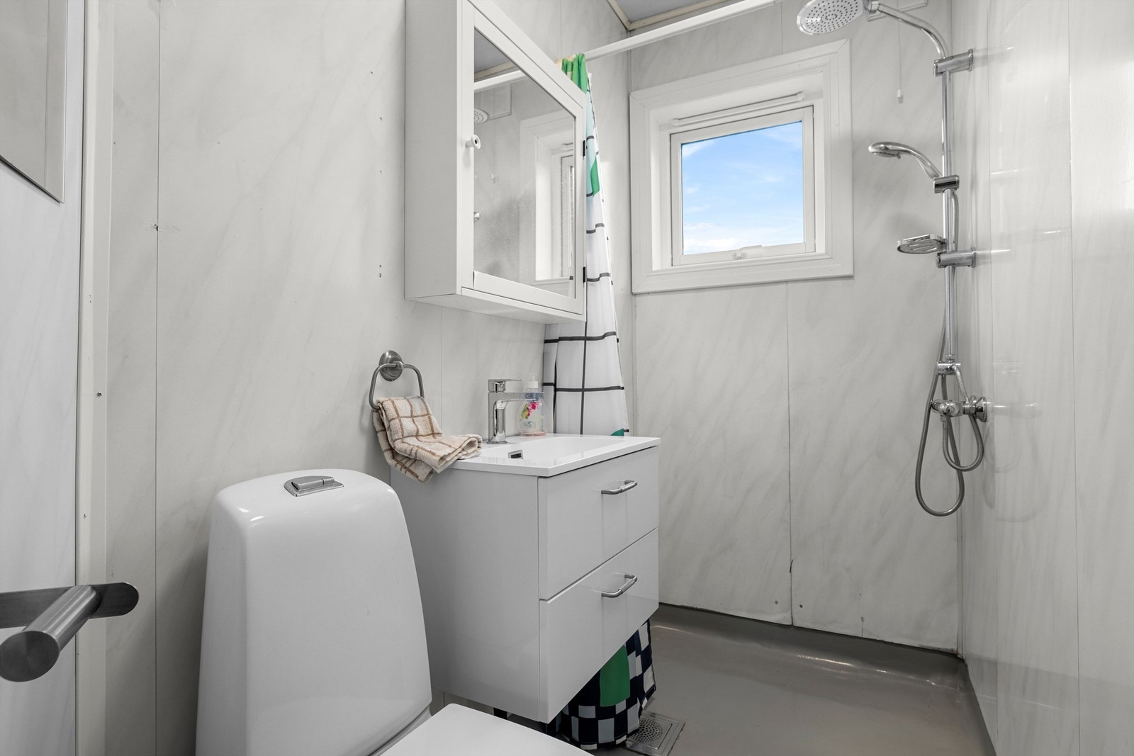 Badet har en funksjonell utforming med dusjhjørne, servant med oppbevaring og toalett. Galleribilde