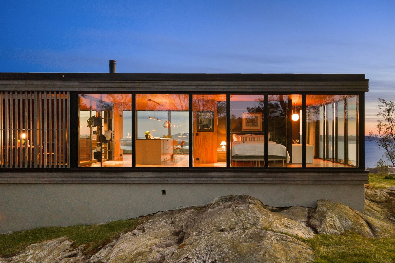 Store glassflater åpner bygget mot naturen og etablerer en sterk visuell og fysisk kontakt mellom inne- og uterom. Galleribilde
