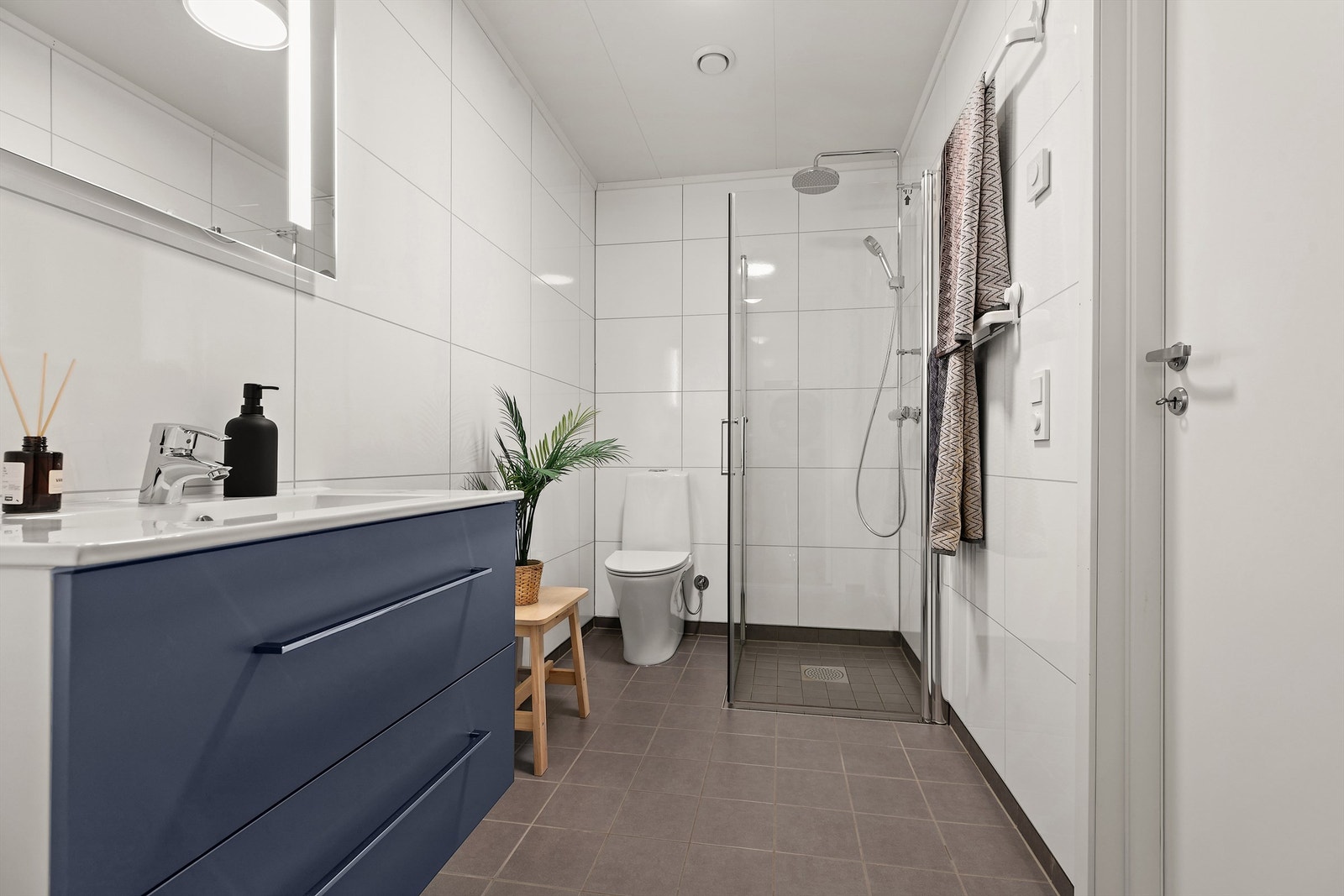 Moderne innredning med heldekkende servant og speil med belysning. Galleribilde