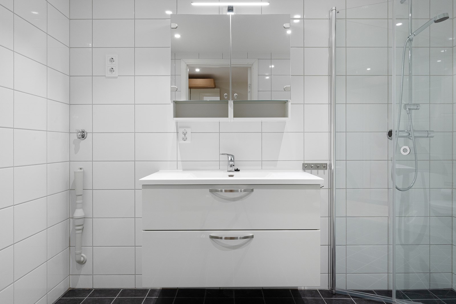 Pent innredet med servant med skuffer og speil overskap. Dusj med innfellbare dører. Downlights. Galleribilde