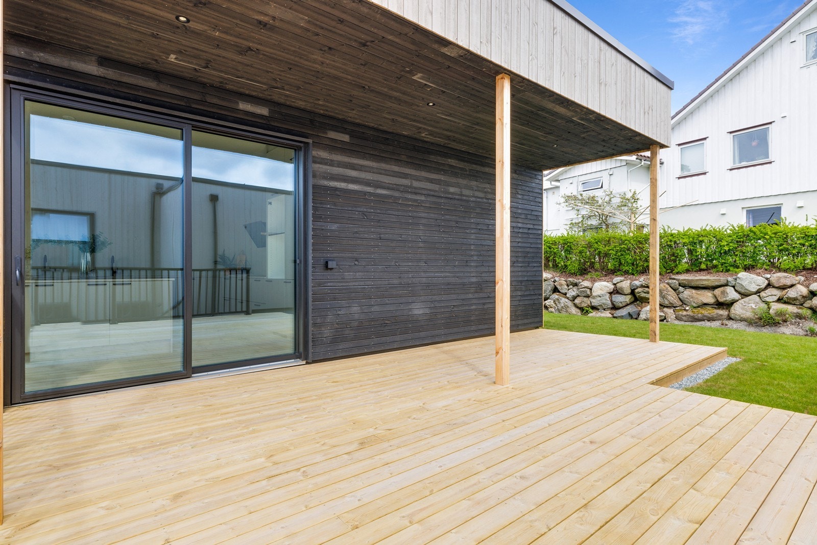 Terrasse med skyvedør fra stue/kjøkken - delvis takoverbygg med spotter til belysning. Galleribilde