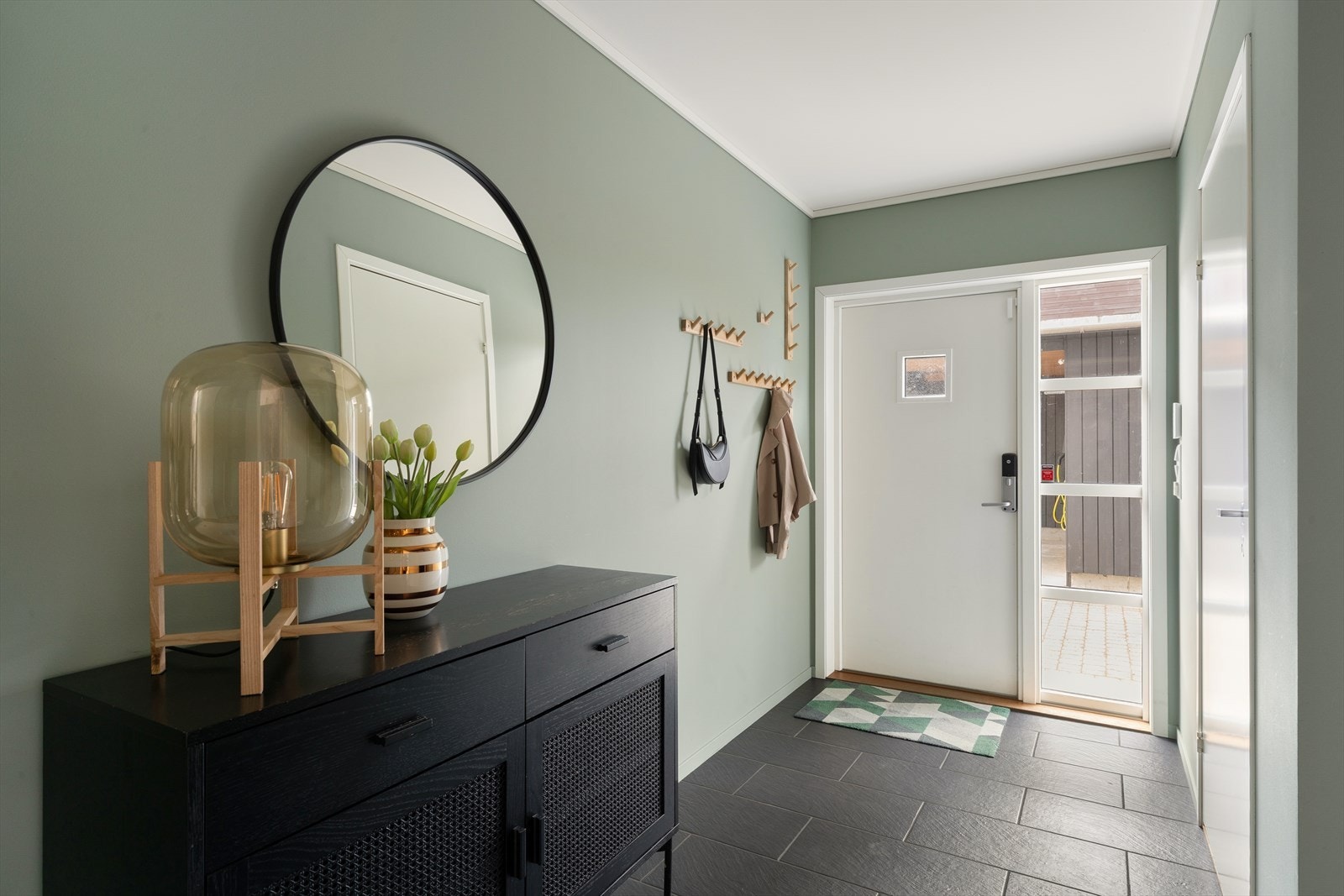 Inngangen til boligen er både funksjonell og estetisk tiltalende, med fliser på gulv og vegger er malt i tidsriktige fargevalg som gir en moderne følelse, samtidig som de er enkle å vedlikeholde. Galleribilde