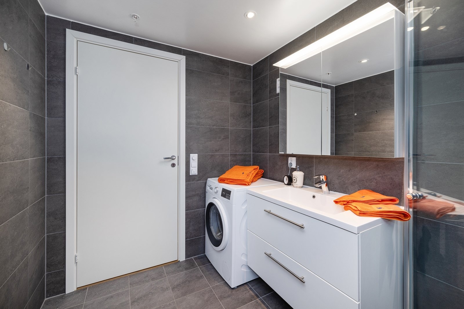Badet har vannbåren gulvvarme, servantinnredning med speilskap og opplegg for vaskemaskin. Galleribilde