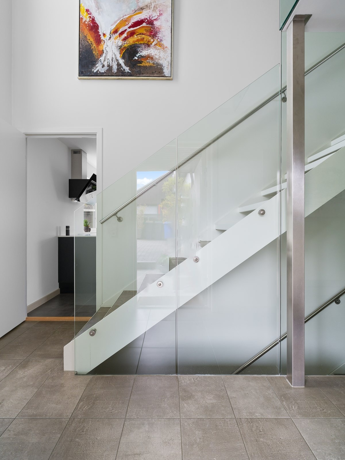 Stilig, minimalistisk trapp i solid stålkonstruksjon med fliser i trinnene og glassdetaljer. Galleribilde