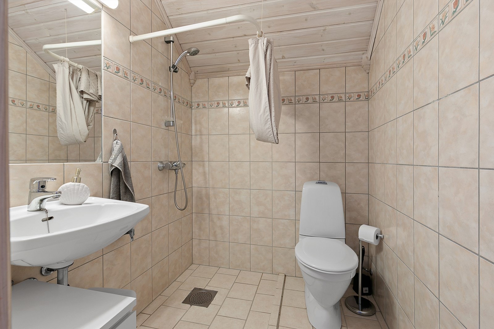 Badet er flislagt med varmekabler, og inneholder dusjhjørne, wc og servant med speil. Galleribilde