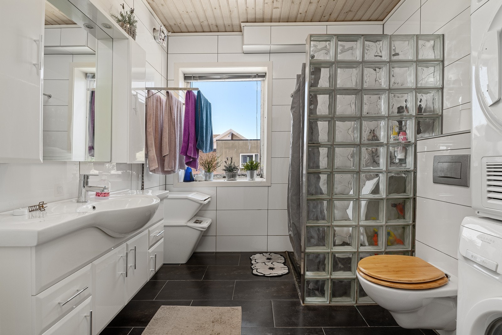 Badet har baderomsinnredning med god oppbevaringsplass, speil og servant, vegghengt toalett og dusj adskilt med glassbyggestein. Galleribilde