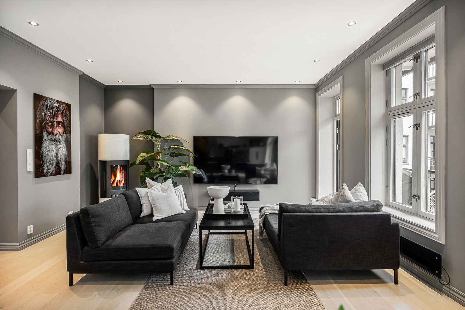 Her er det god plass til både sofagruppe og øvrig møblement, og den frittstående vedovnen tilfører en lun og hyggelig stemning som understreker leilighetens varme og hjemlige preg. Galleribilde