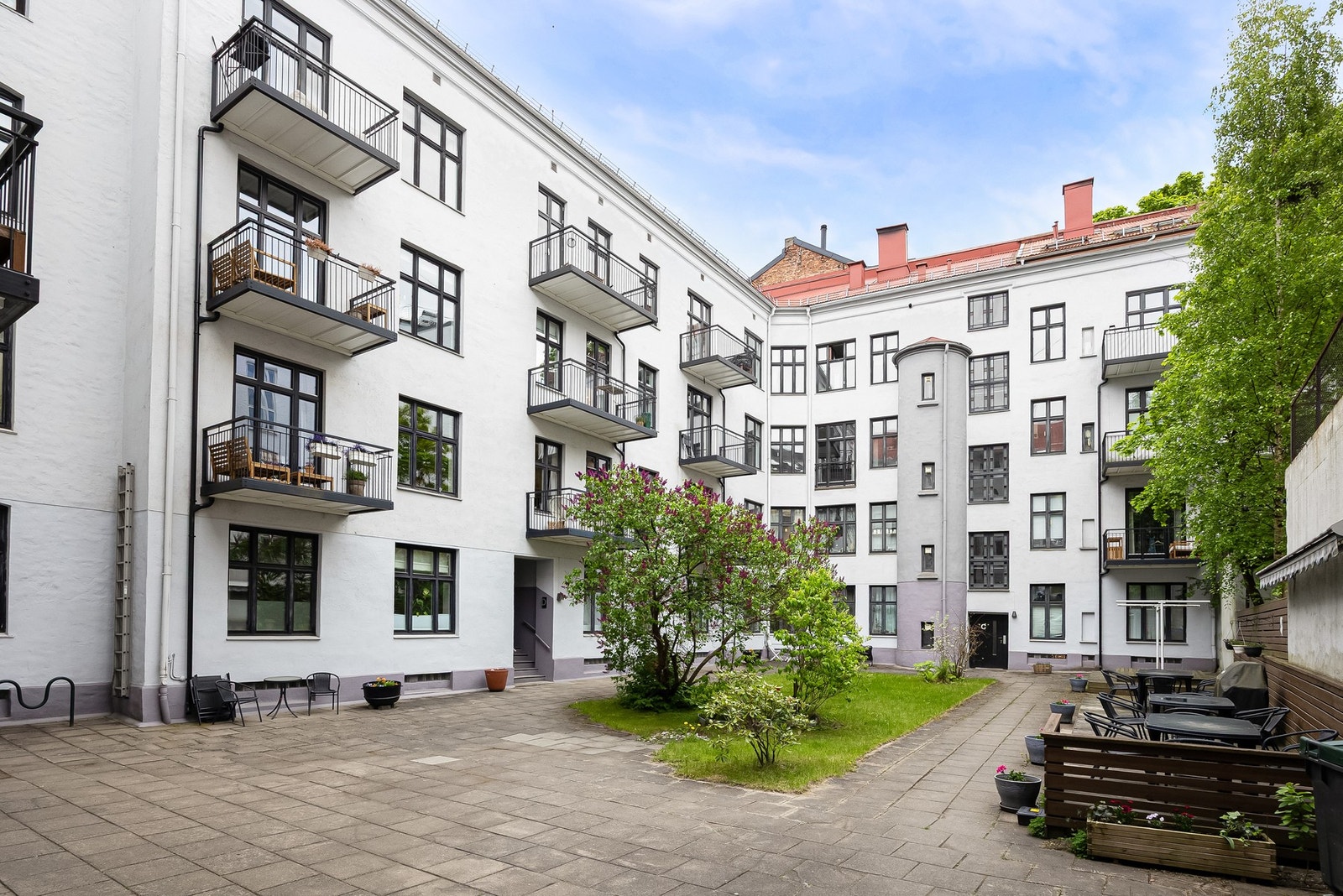 Svært hyggelig bakgård med grønne trær, beplantning, busker og sitteplass. Galleribilde
