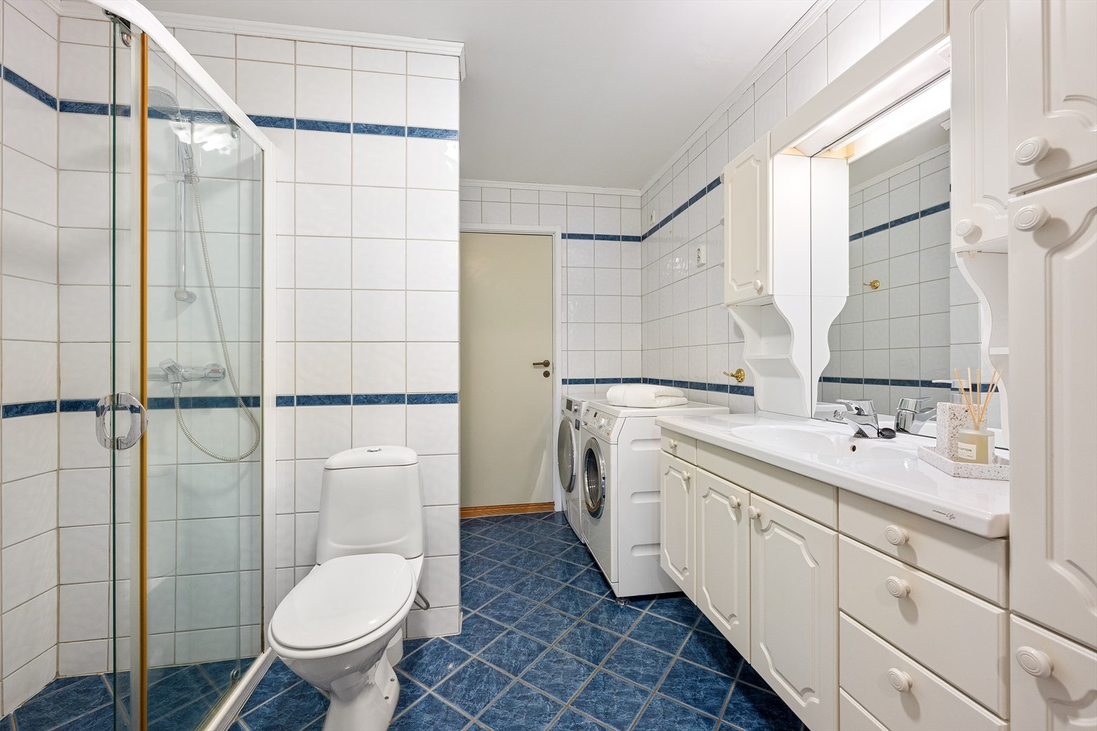 Flislagt bad utstyrt med dusj, wc, servant og opplegg for vaskemaskin Galleribilde