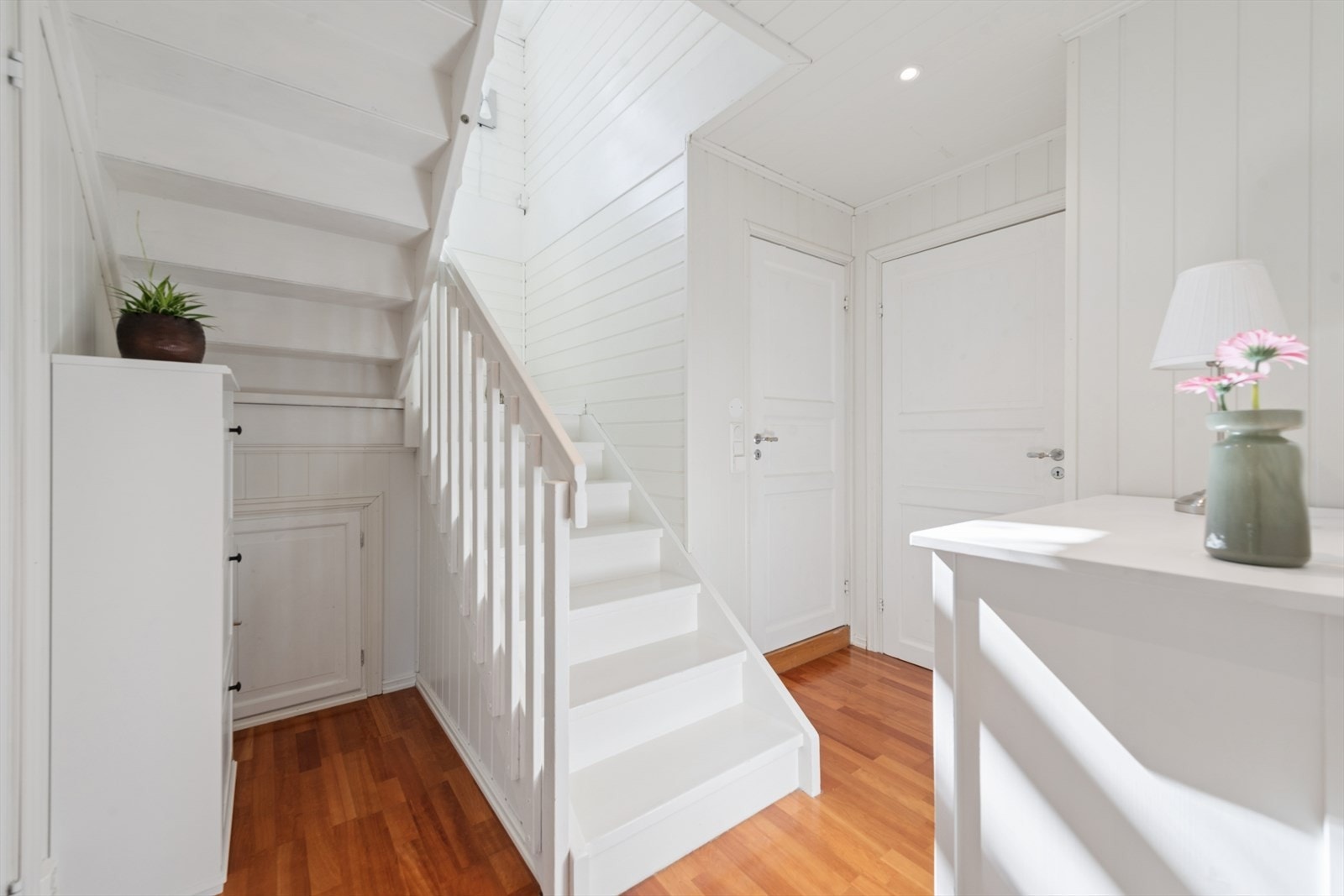 Innkledd trapp som forbinder etasjene. Gangen i underetasjen fikk nytt tak med downlights i 2010. Galleribilde