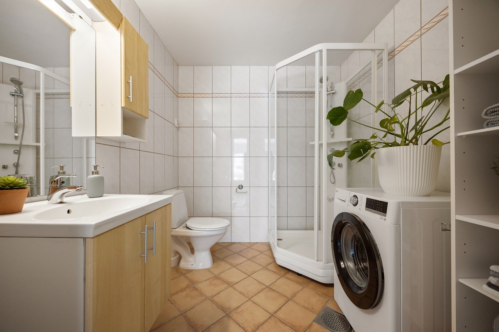 Badet er praktisk innredet med servantskap med ett-greps blandebatteri, veggspeil, lysarmatur, veggskap, gulvstående toalett og dusjkabinett. Det er opplegg for vaskemaskin. Galleribilde