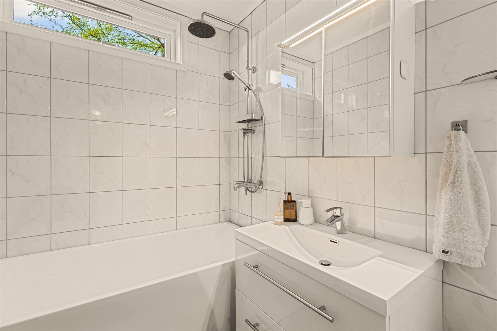 - Badet er innredet med badekar med dusjarmatur, toalett, speilskap med belysning og servant med møblement - Galleribilde